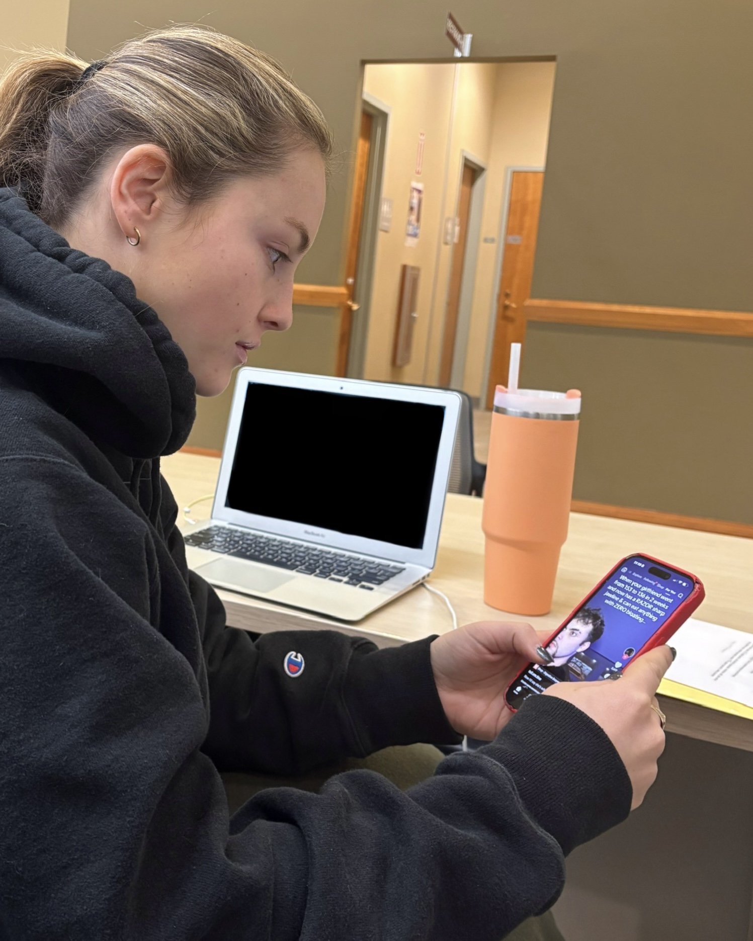 Paige Long ’27 scrolling through TikTok on her phone in the Schaffer Library.