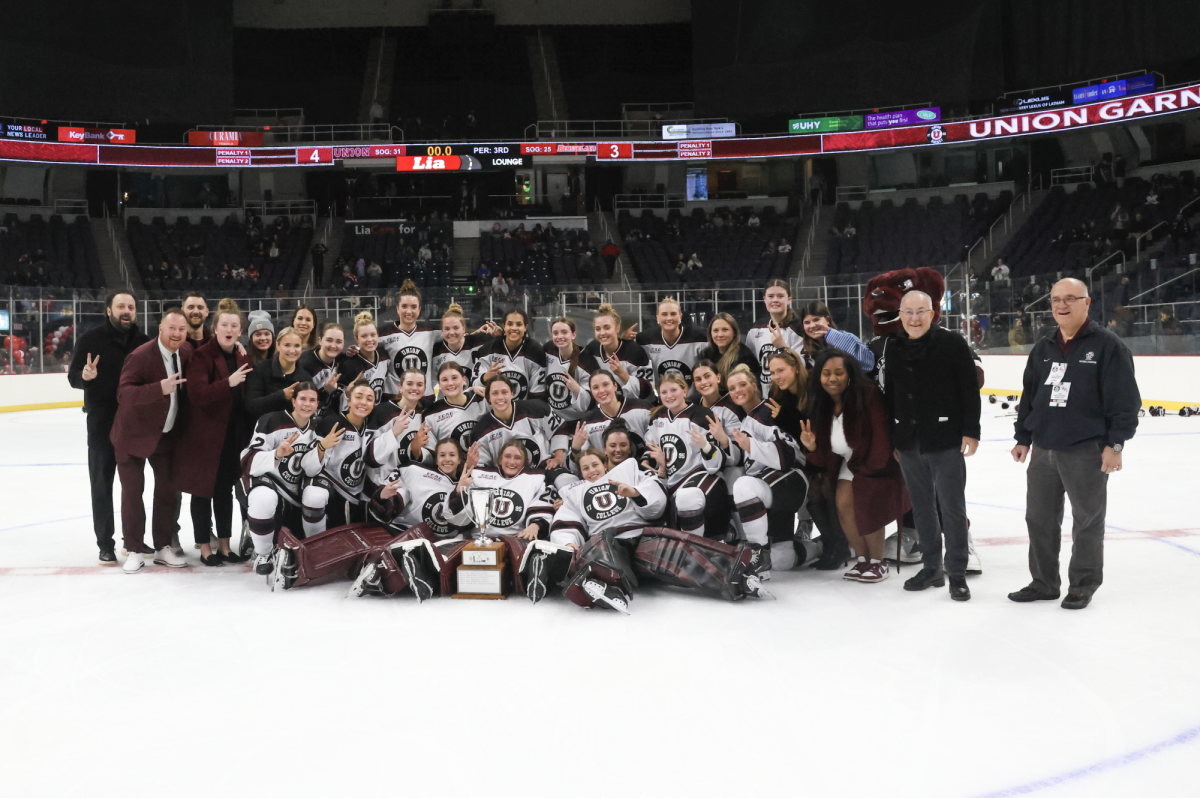 The women’s hockey team posing with the trophy following their win on Saturday.