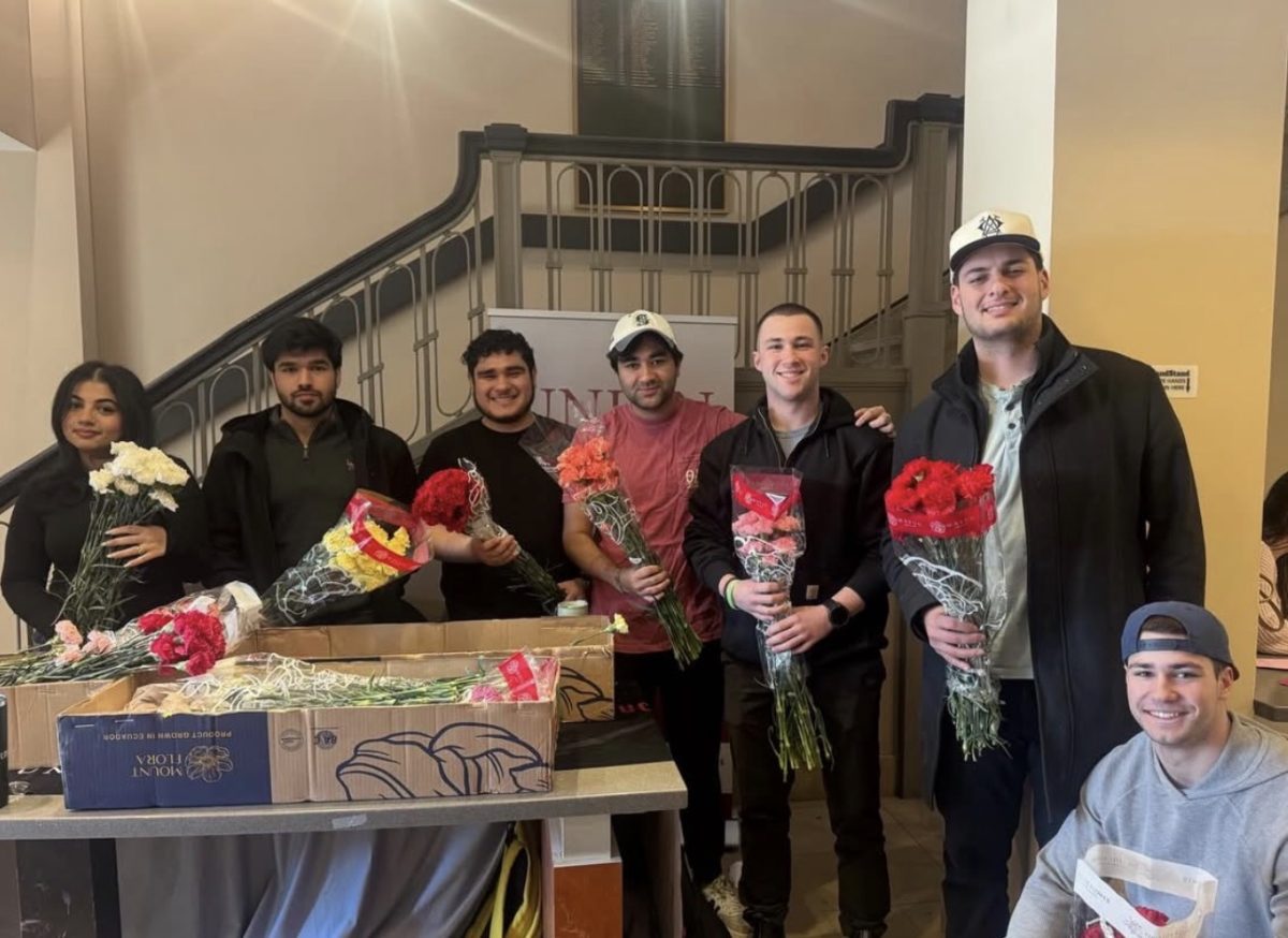 Theta Delta Chi brothers and CPN Resident Assistants distributing flowers at Reamer Campus Center.